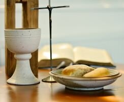 A table with a cup and bread prepared for communion.