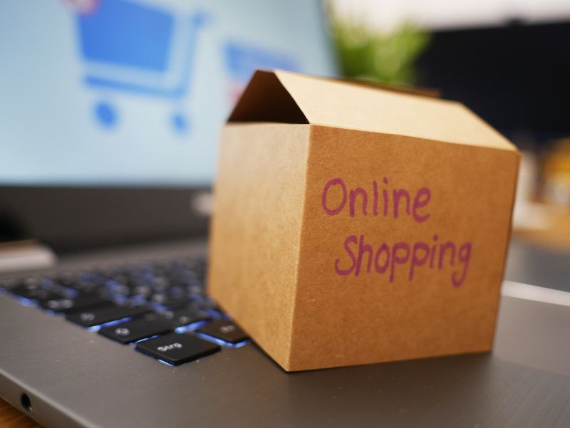 Cardboard box with the words "Online Shopping" written on the side, placed on top of a laptop